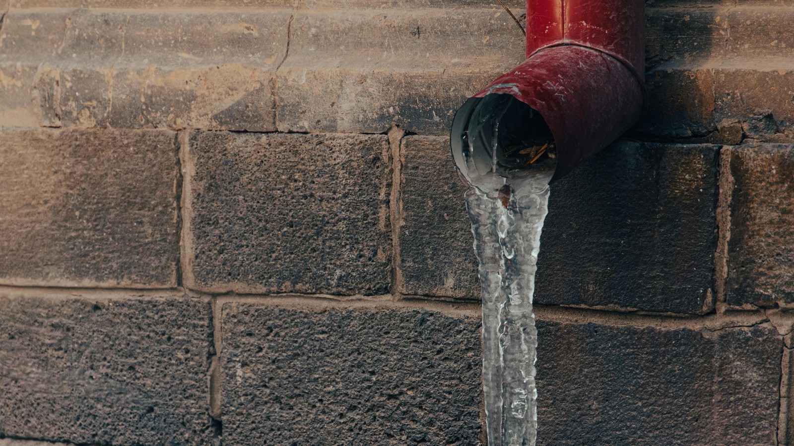 Frozen exterior pipe covered in ice during winter